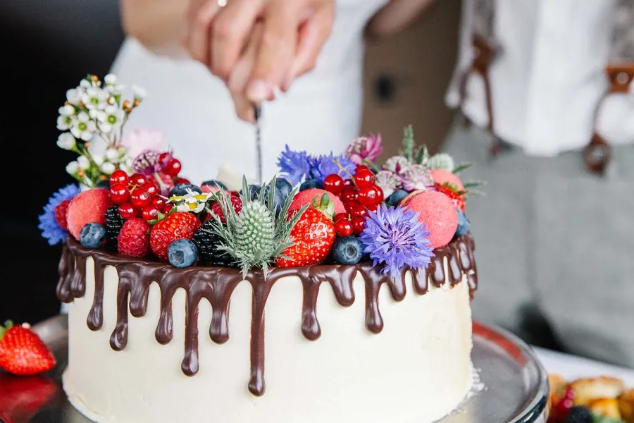 Torte mit Beeren, Blumen und Schokoladenguss wird bei einer Feier in Ahrenshoop angeschnitten.