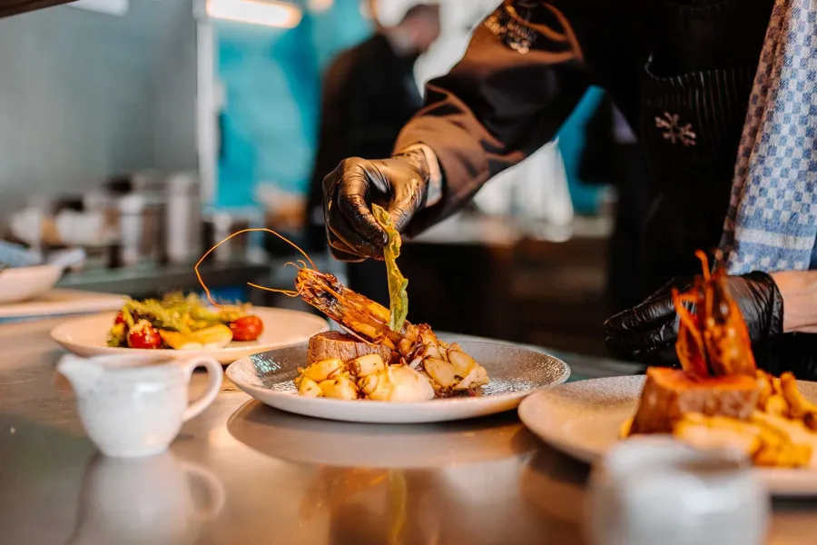 Chef de Partie (m/w/d) richtet ein hochwertiges Gericht in der Küche des THE GRAND Ahrenshoop an.