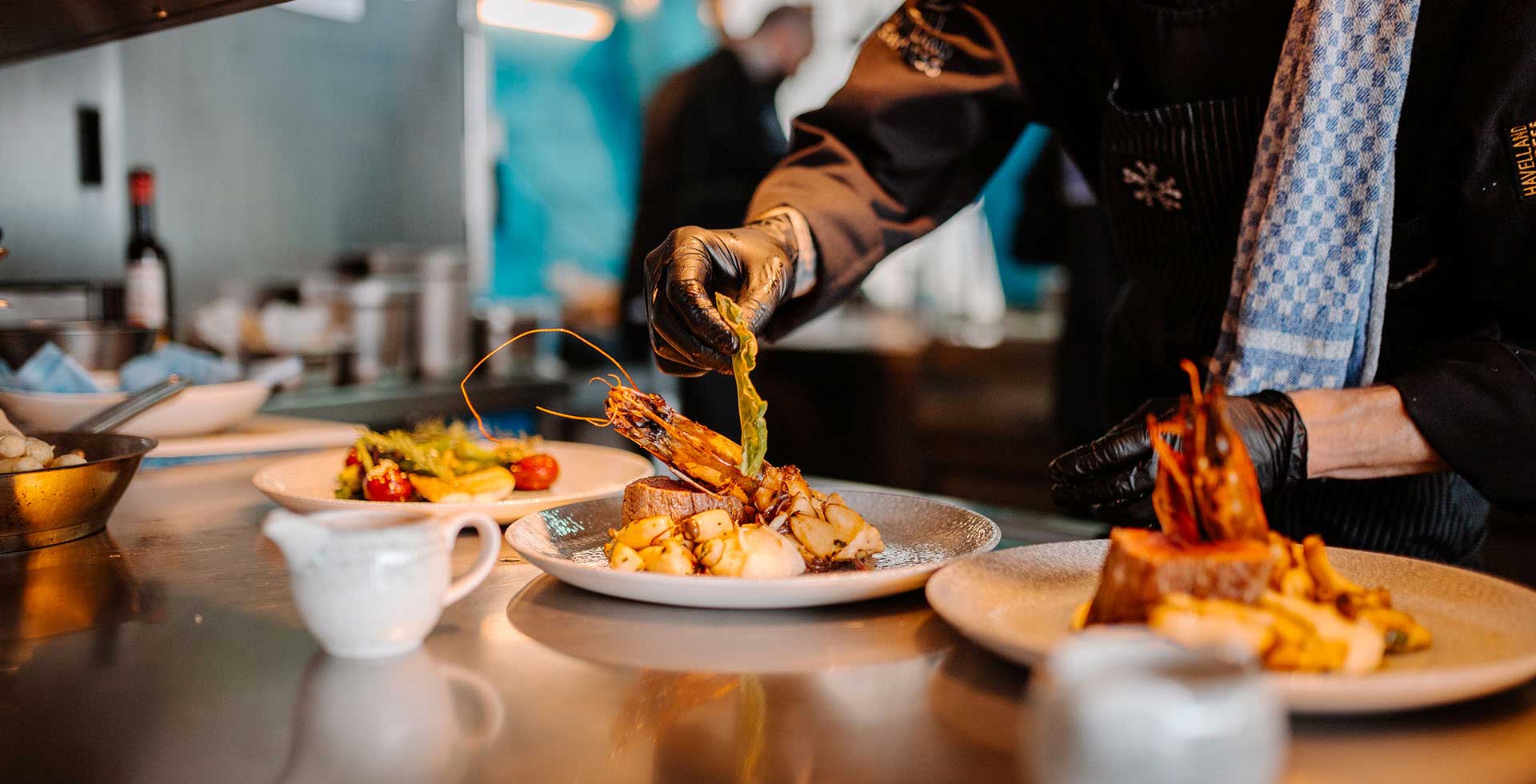 Chef de Partie (m/w/d) richtet ein hochwertiges Gericht in der Küche des THE GRAND Ahrenshoop an.