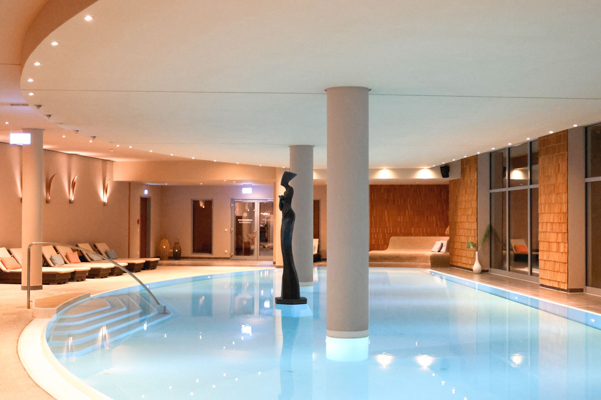 Innenpool im Spa an der Ostsee mit Liegen, warmem Licht und ruhiger Atmosphäre.