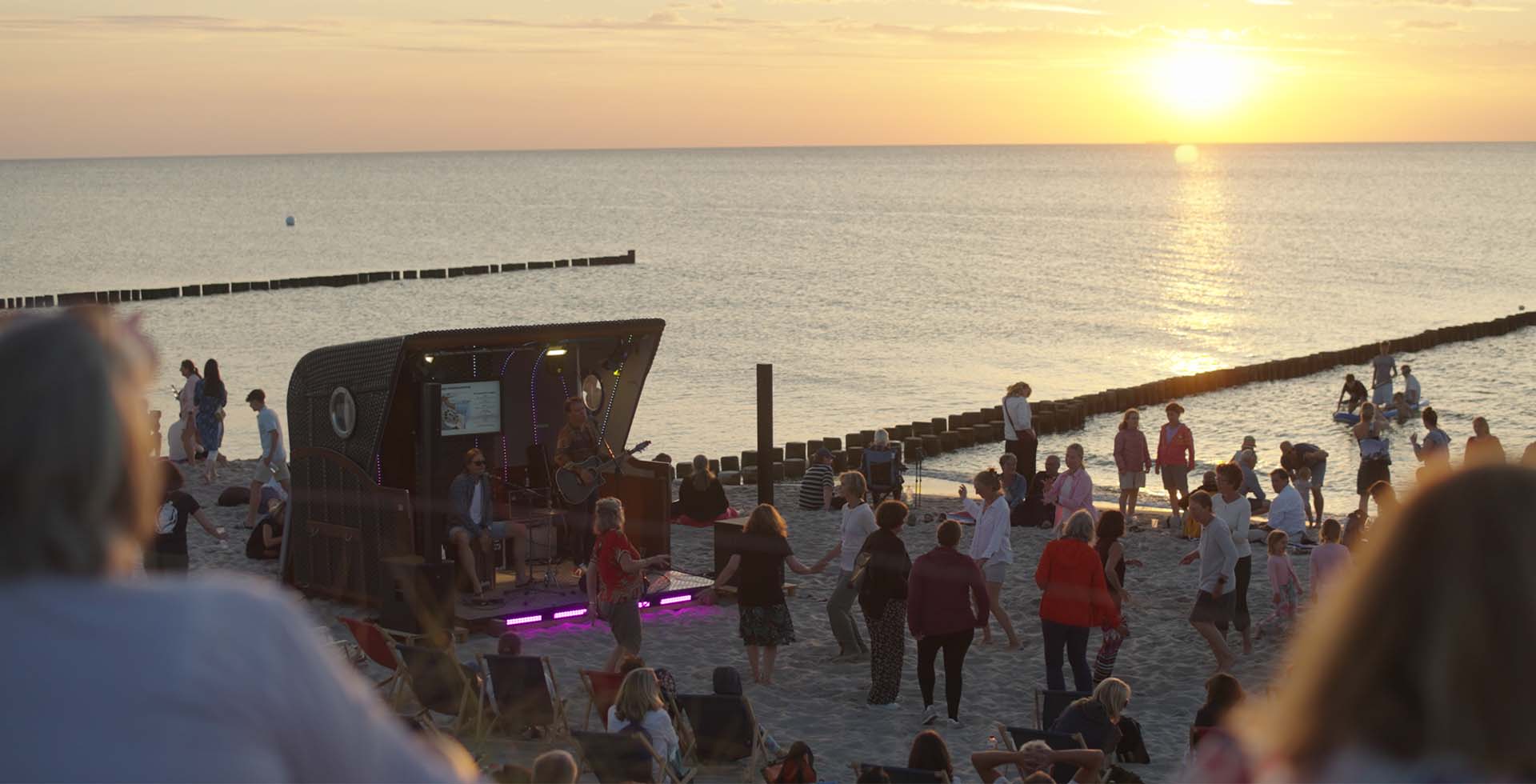 Sommerabend am Strand bei Ahrenshoop mit Bühne, Publikum und Sonnenuntergang an der Ostsee.