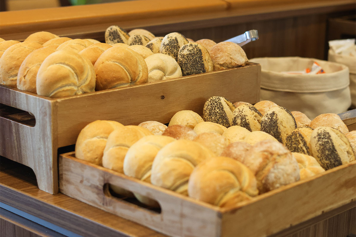Frische Brötchen liegen sortiert in Holzkisten auf einem Frühstücksbuffet an der Ostsee.