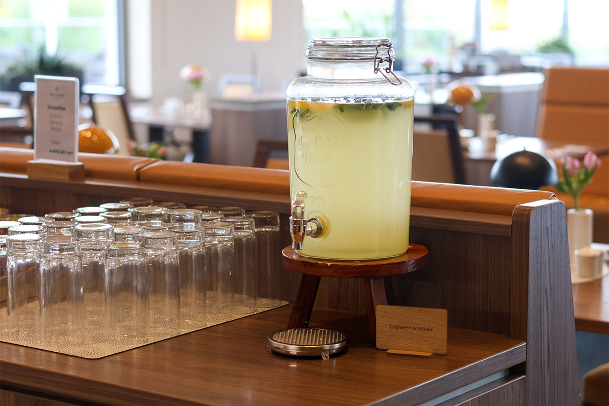 Glasbehälter mit Ingwerwasser steht am Frühstücksbuffet des THE GRAND Ahrenshoop neben sauberen Gläsern.