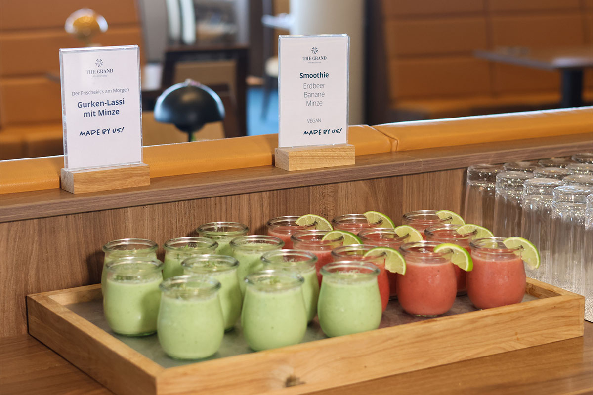 Kleine Gläser mit grünem Gurken Lassi und rotem Smoothie stehen am Frühstücksbuffet im THE GRAND Ahrenshoop.