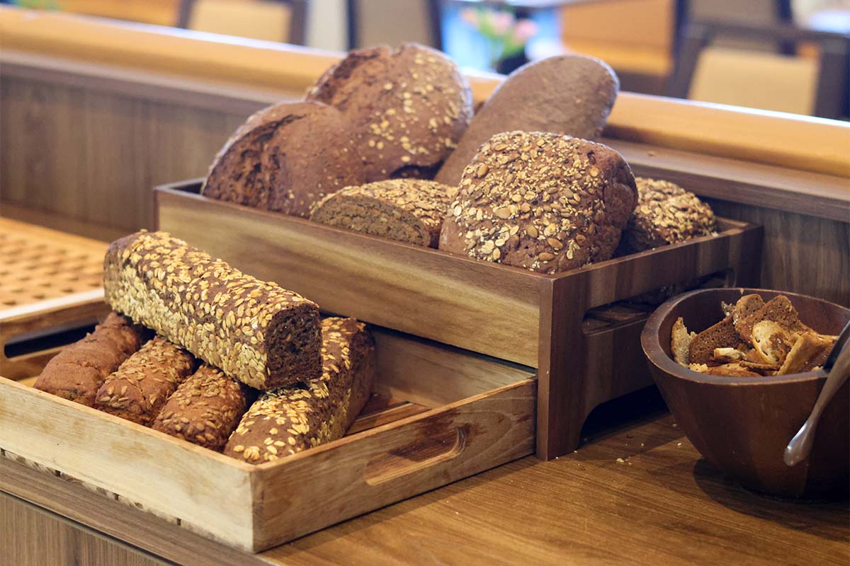 Mehrere Vollkornbrote und Körnerbrötchen liegen in Holzkisten am Frühstücksbuffet an der Ostsee.