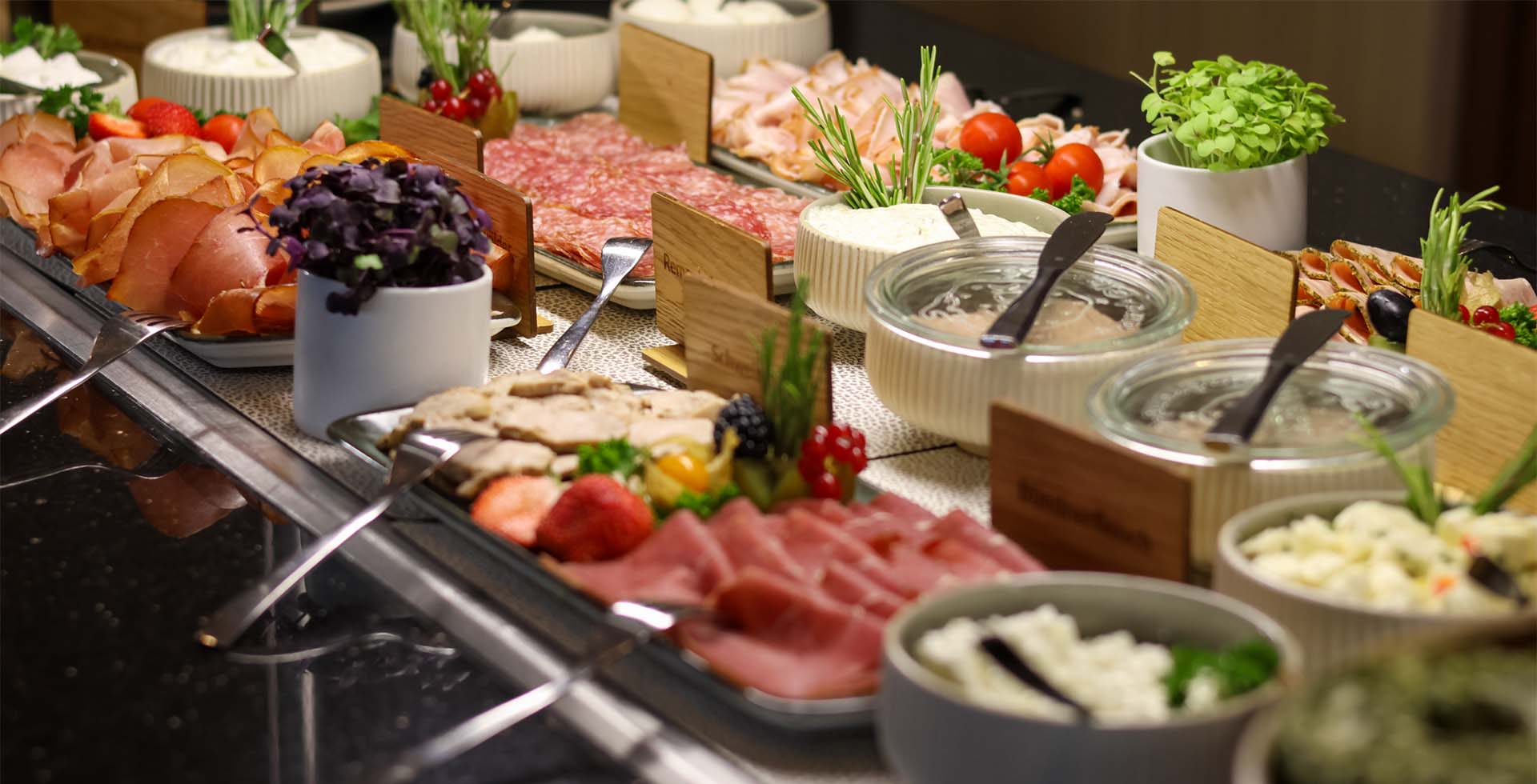 Aufschnitt, Salami, Käse und frische Beilagen liegen am Frühstücksbuffet im THE GRAND Ahrenshoop.