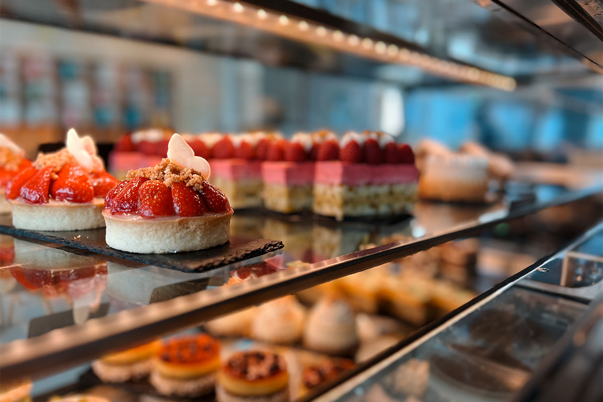 Erdbeertörtchen und weitere Desserts stehen in der Vitrine der THE GRAND Patisserie.