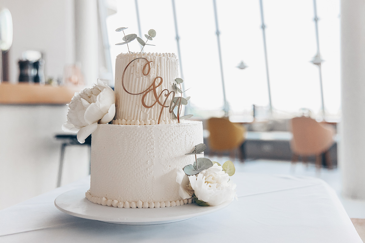 Zweistöckige Hochzeitstorte mit Blumen steht in einem hellen Raum an der Ostsee.