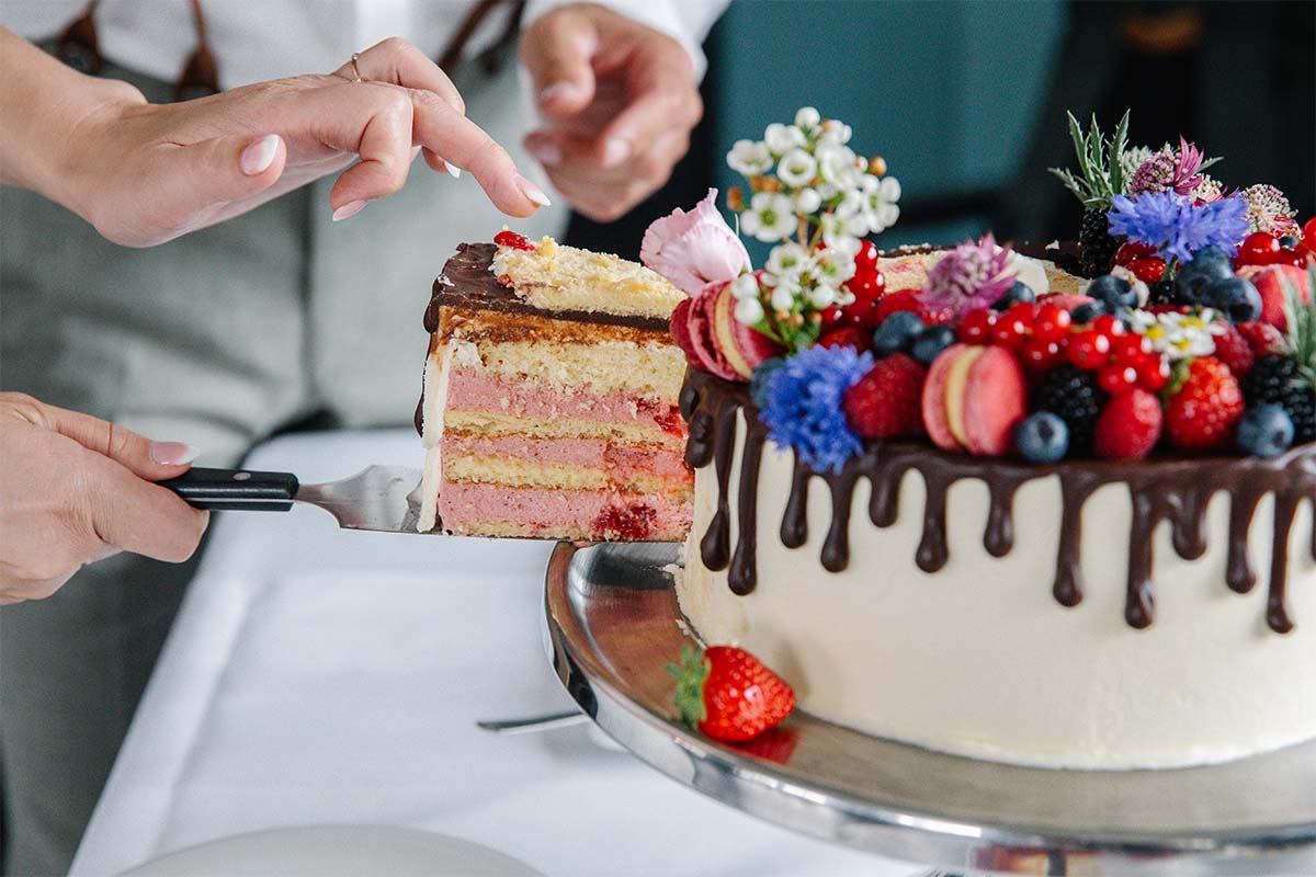 Torte mit Beeren und Schokoladenguss wird auf einer Etagere in Ahrenshoop angeschnitten.