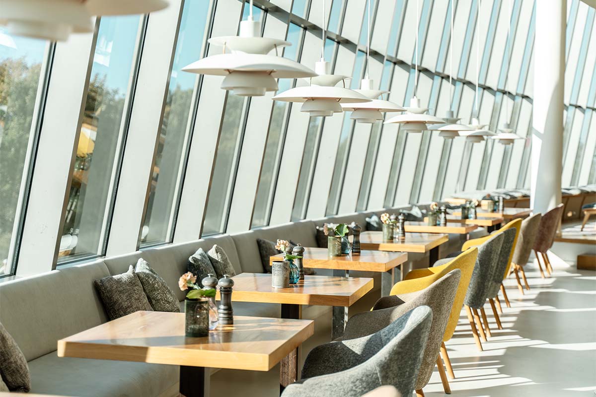 Tische am Fenster im SEASIDE Restaurant mit großer Glasfront und Blick Richtung Ostsee.