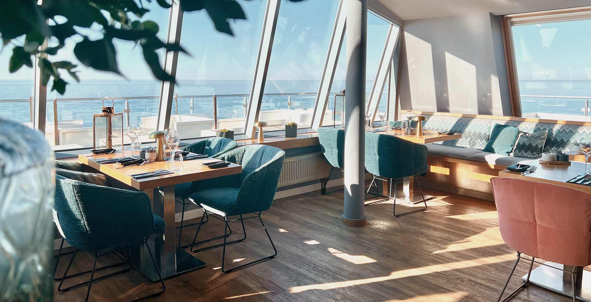 Helle Sitzplätze mit bodentiefen Fenstern und Ostseeblick im Restaurant WEITBLICK auf dem Darß.