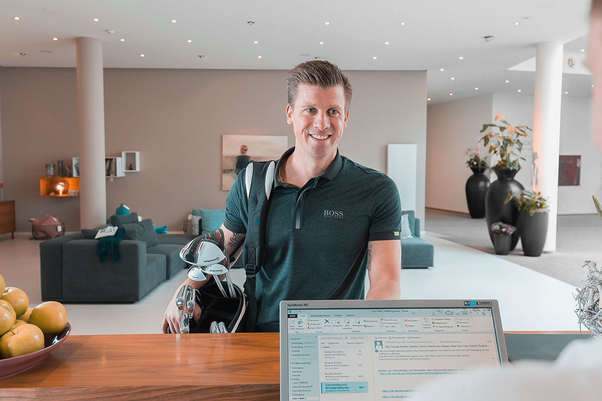 Gast mit Golfschlägern an der Rezeption zur Anmeldung für Golf an der Ostsee.