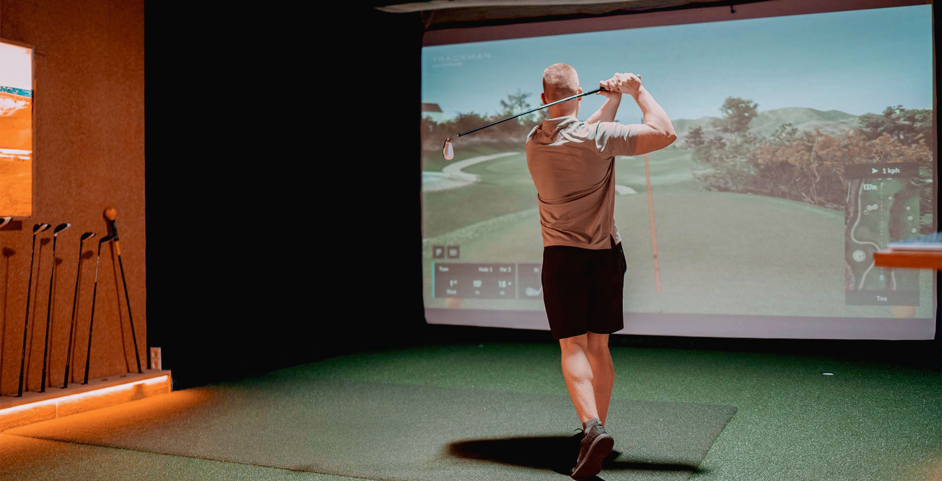 Mann beim Schwungtraining im Indoor-Golfbereich des THE GRAND Ahrenshoop vor großer Projektionsleinwand.