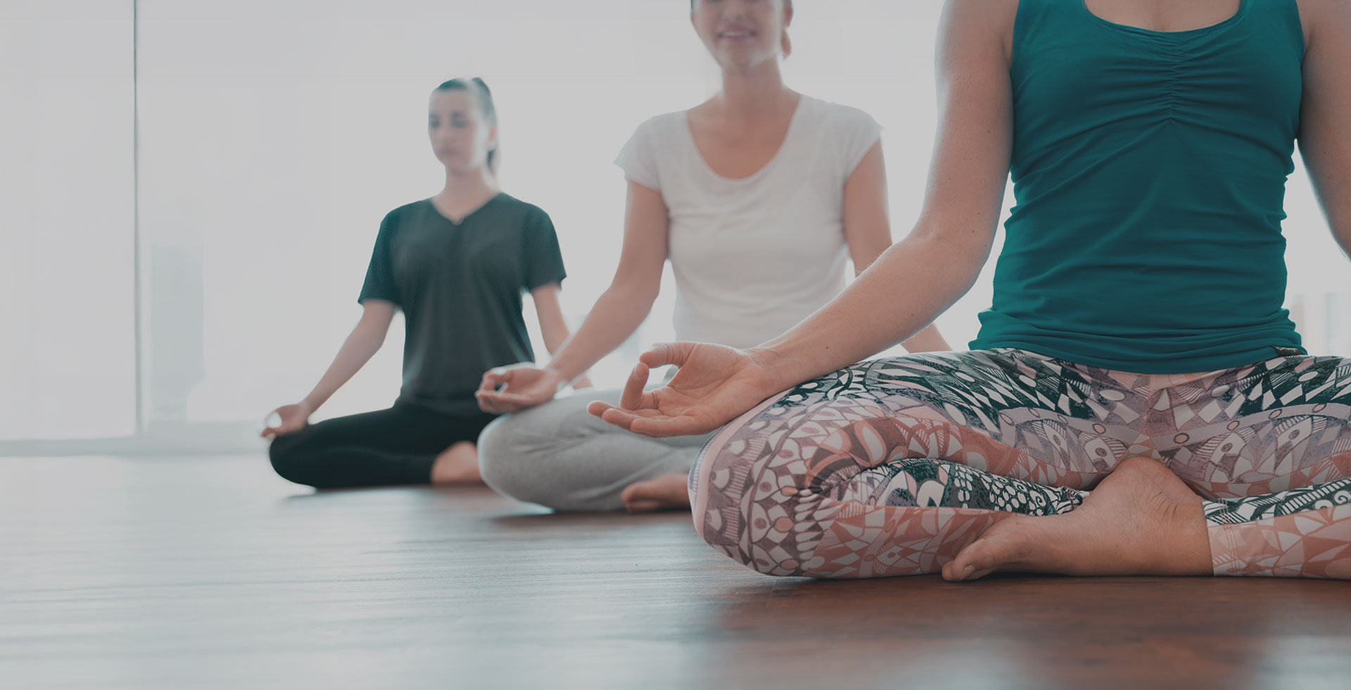 Yoga Teilnehmende im Schneidersitz bei einer Meditationsübung an der Ostsee.
