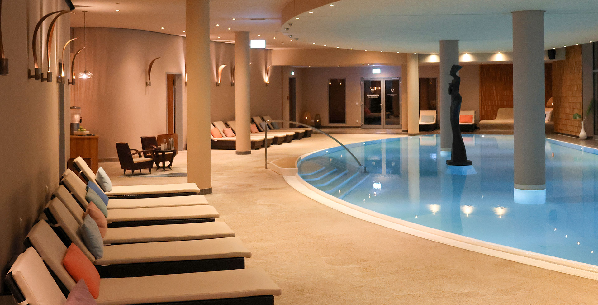 Innenpool mit Liegen und warmem Licht im großzügigen Spa-Bereich an der Ostsee.