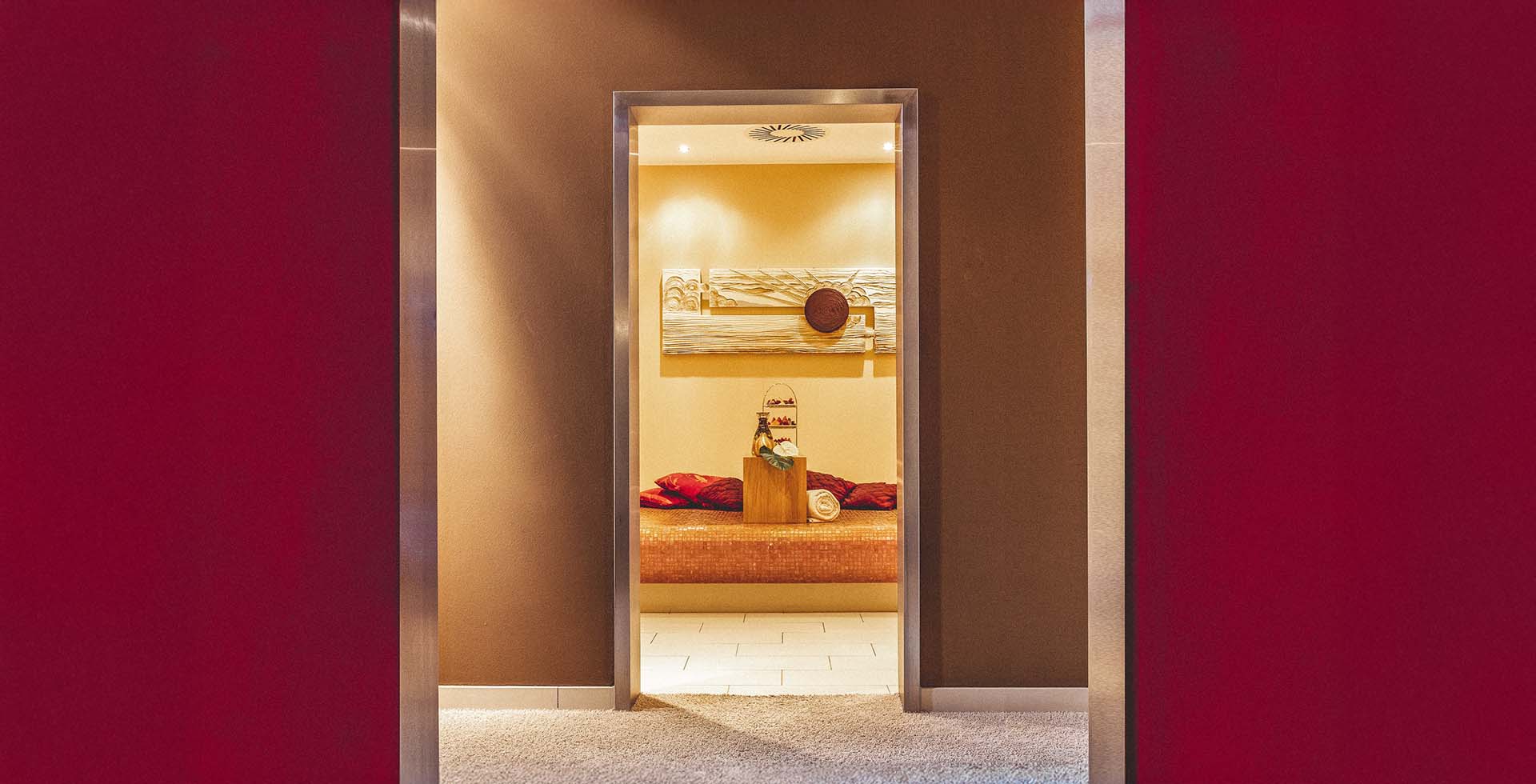 Eingang zu einem warm beleuchteten Ruheraum mit Liege und Wellnesszubehör im Spa an der Ostsee.