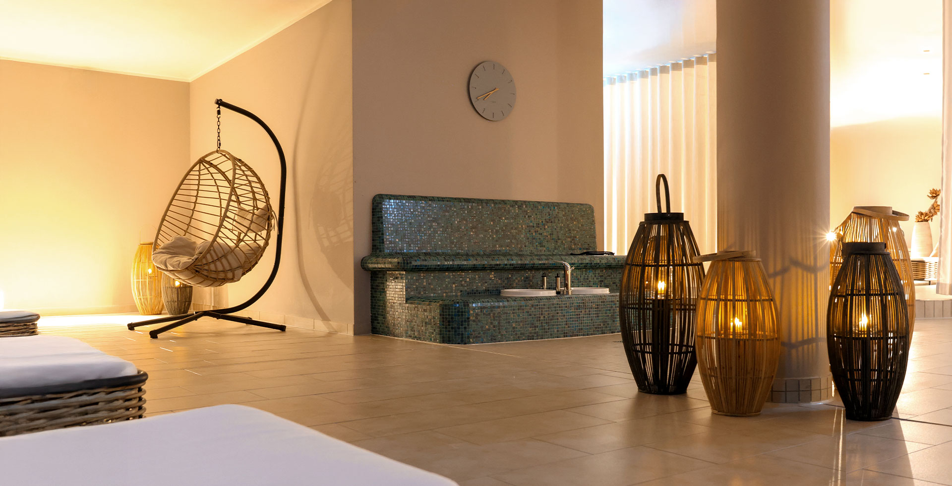 Stilvoller Wellnessbereich mit Hängesessel, Fußbecken und dekorativen Laternen im Spa des THE GRAND Ahrenshoop.